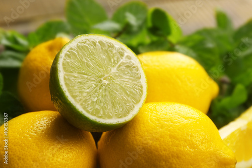 Fresh lemons and half of lime with green leaves closeup