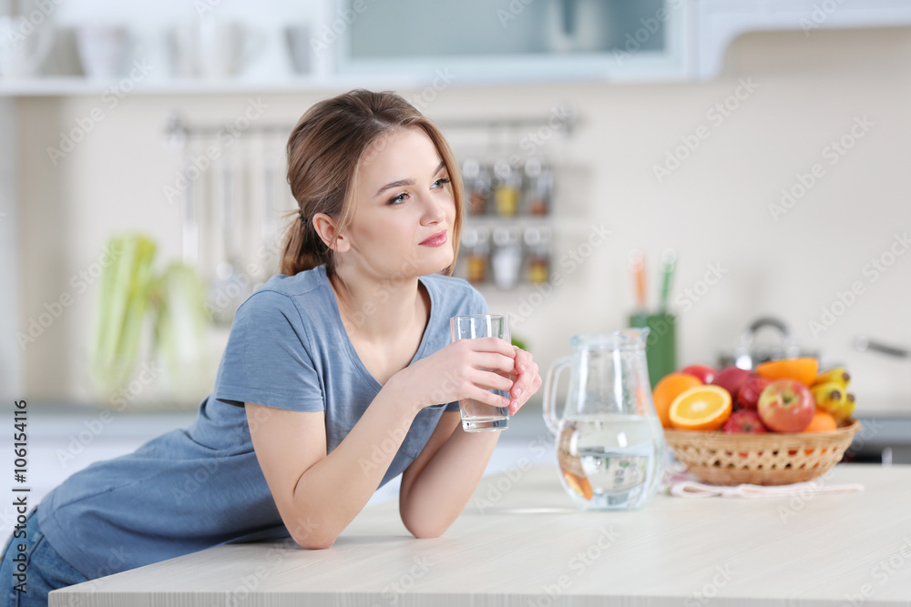 Young woman drinking water from glass in the kitchen Young woman drinking water from glass in the kitchen