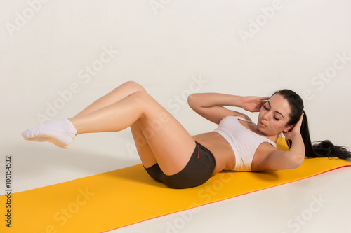 attractive woman doing exercises. Brunette fit body on yoga mat