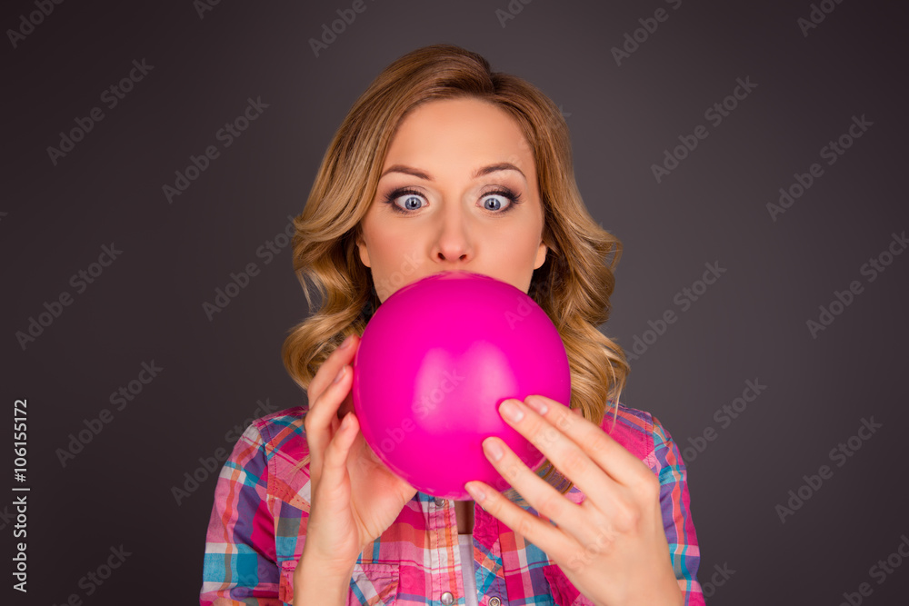 Portrait of young blonde trying to inflate pink balloon Portrait of young blonde trying to inflate pink balloon