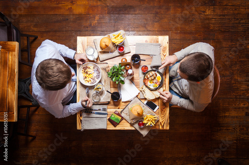Young men having meal at cafe, view from above