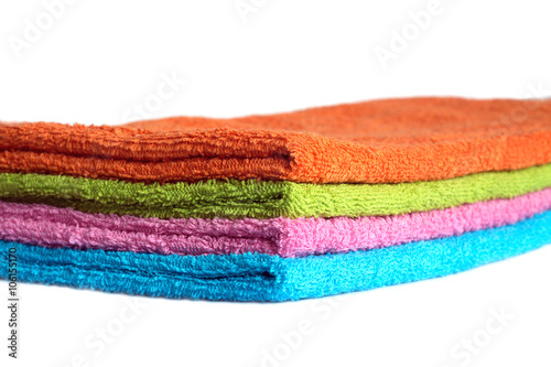 Four clean soft double bath towels set of different colors stacked isolated on white background. Side view from corner close-up
