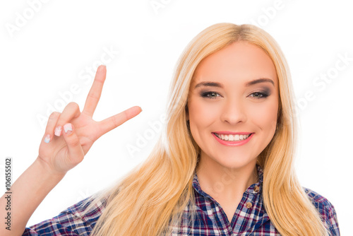 Portrait of cheerful young blonde gesturing with two fingers