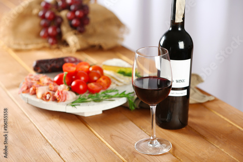Fototapeta Naklejka Na Ścianę i Meble -  Glass and bottle of red wine with food on table closeup