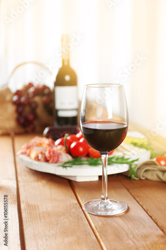 Glass of red wine with food on wooden table closeup