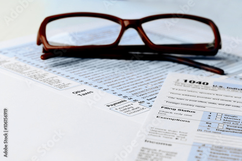 1040 Individual Income Tax Return Form with  brown rimmed glasses isolated on the white background  close up
