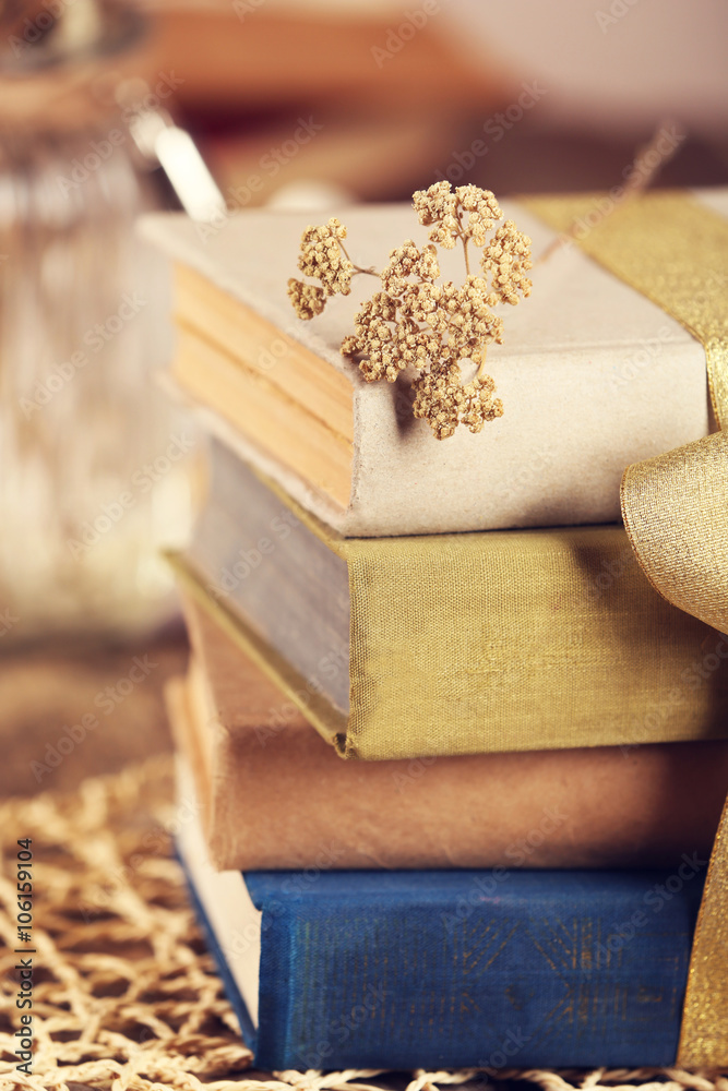 Fototapeta premium Stack of old books tied with yellow ribbon on a table, close up