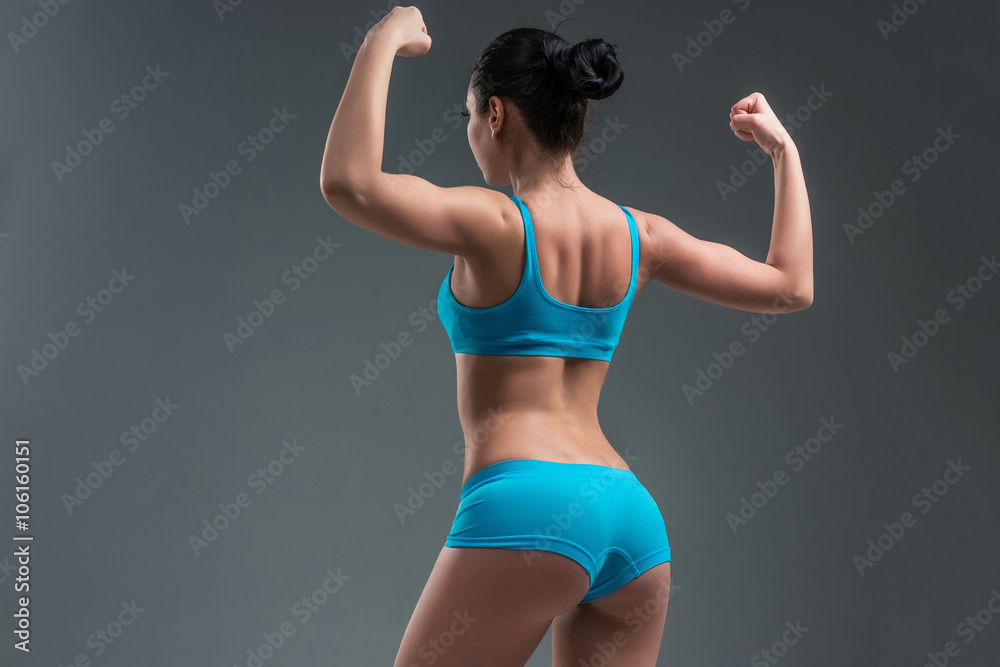Obraz premium young athletic girl shows muscles