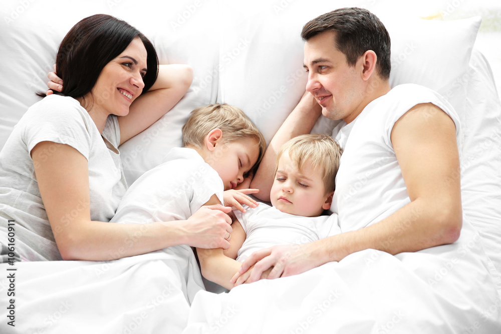Family smiling in bed under blanket, closeup Family smiling in bed under blanket, closeup