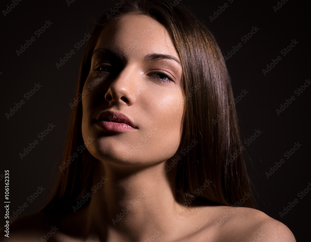 Fototapeta premium Portrait of beautiful brunette woman with natural look and without makeup on black background