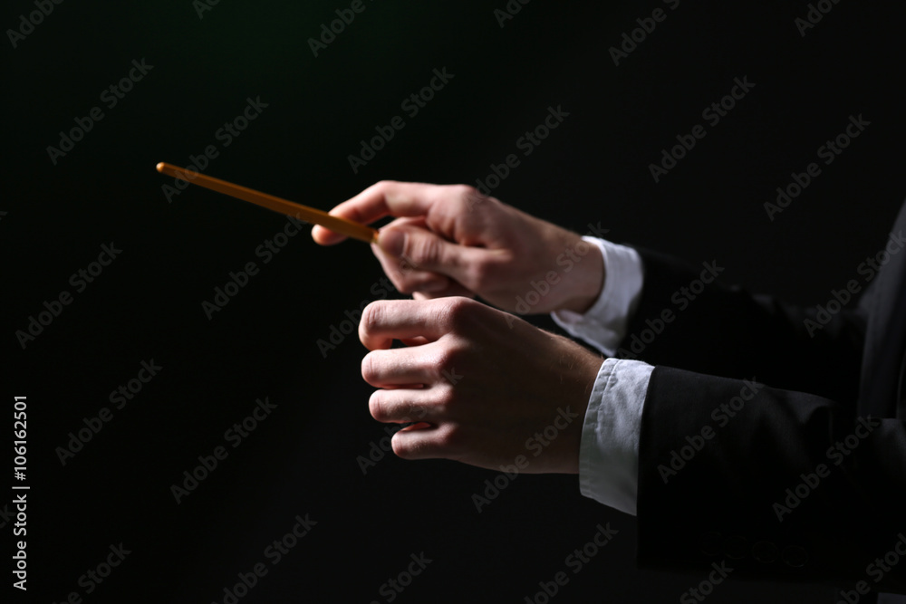 Music conductor directing with baton on black background, close up Music conductor directing with baton on black background, close up