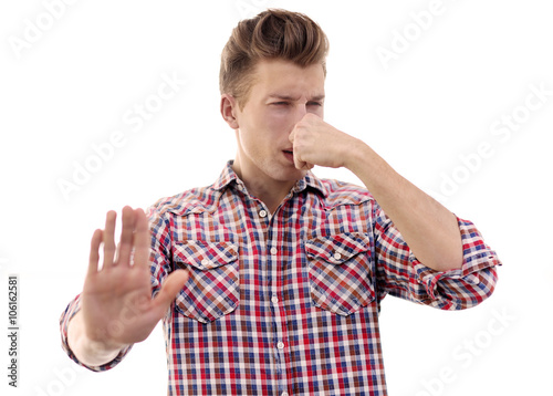 Young blonde man pinching his nose because of the stench, isolated on white