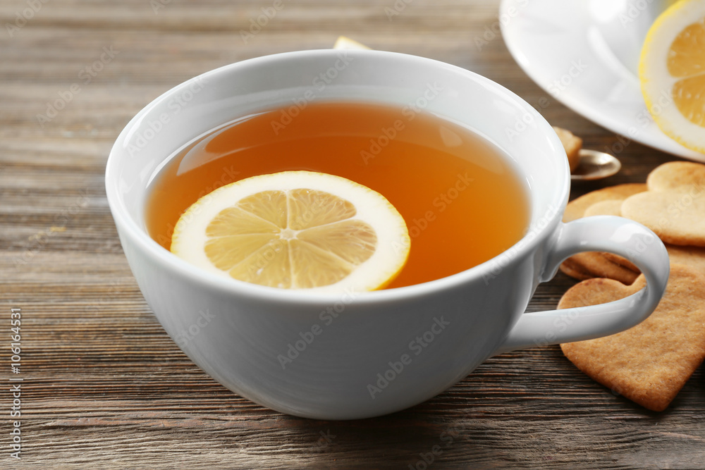 Cup of brewed tea with lemon, and cookies on wooden table Cup of brewed tea with lemon, and cookies on wooden table