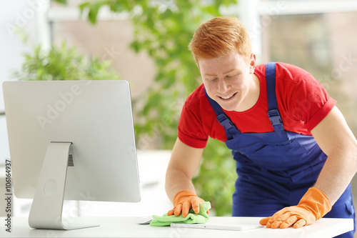 Young janitor cleaning tabl...