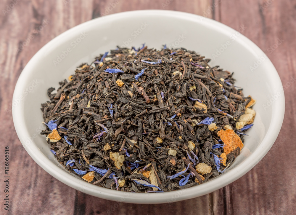 Dried black Earl Grey tea leaves in white bowl over wooden background Dried black Earl Grey tea leaves in white bowl over wooden background