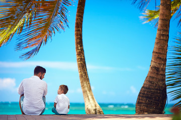 happy father and son sitting together near the seaside