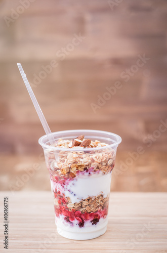 yogurt with granola,honey, almond and fresh berries on wooden board