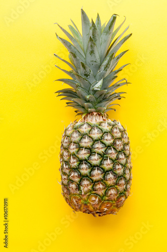 Natural and complete pineapple on a solid yellow background and flat