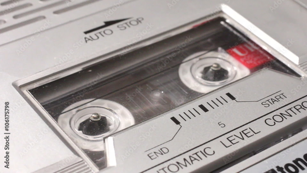 Putting an audio music cassette tape into a recorder and switching to play.