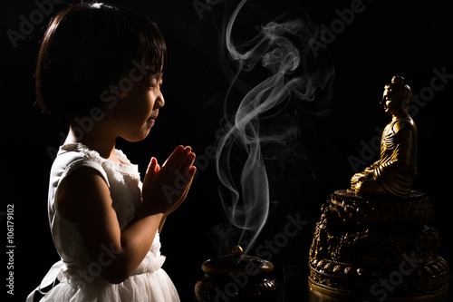 Asian Little Chinese Girl Praying in front of Buddha photo