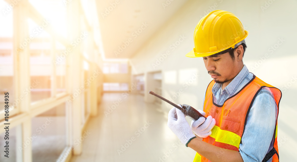 Confident supervisor using walkie-talkie at construction site Confident supervisor using walkie-talkie at construction site
