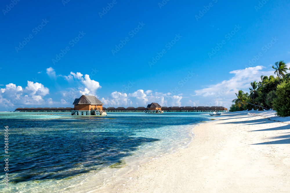 Пляж на Мальдивских островах на фоне двух вилл на воде для новобрачных