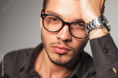 man with glasses holding his hand on his head