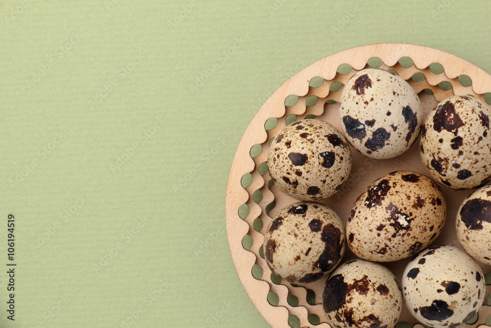 Easter background. / Quail eggs on a wooden plate. Green background.