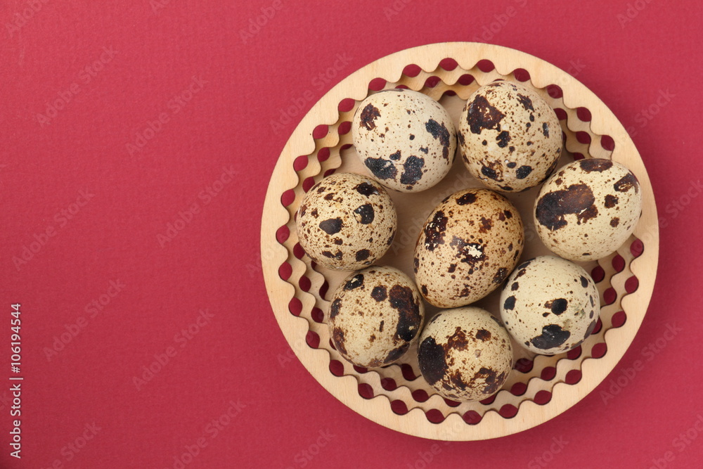 Easter background. / Quail eggs on a wooden plate. Red background.