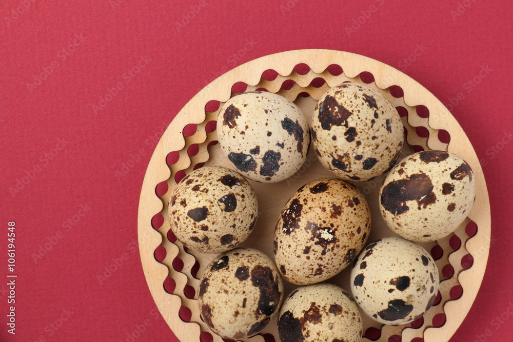 Easter background. / Quail eggs on a wooden plate. Red background.