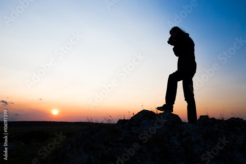 Silhouette of longhair male model with camera.
