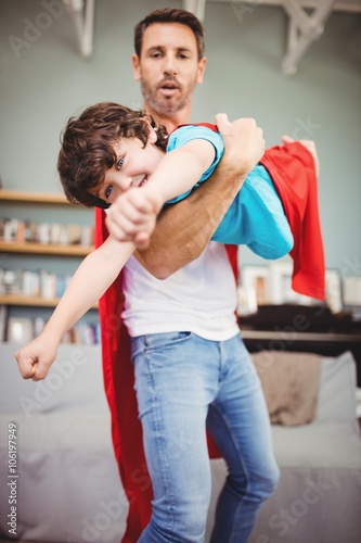 Father holding son wearing superhero costume