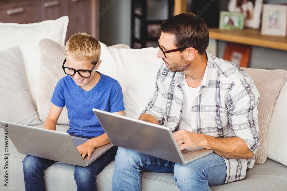 Father and son wearing eyeglasses while working on laptop Father and son wearing eyeglasses while working on laptop