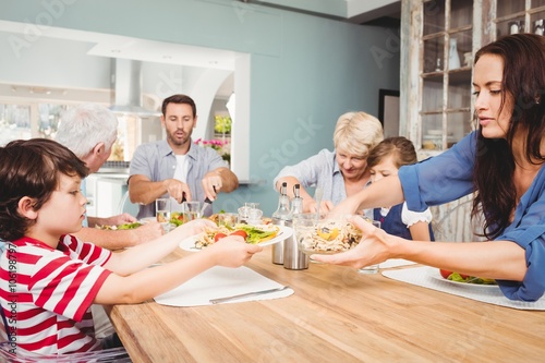 Mother giving food to son while sitting at dining table
