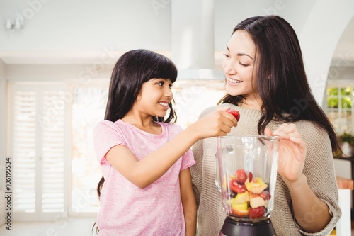 Mother and daughter preparing fruit juice