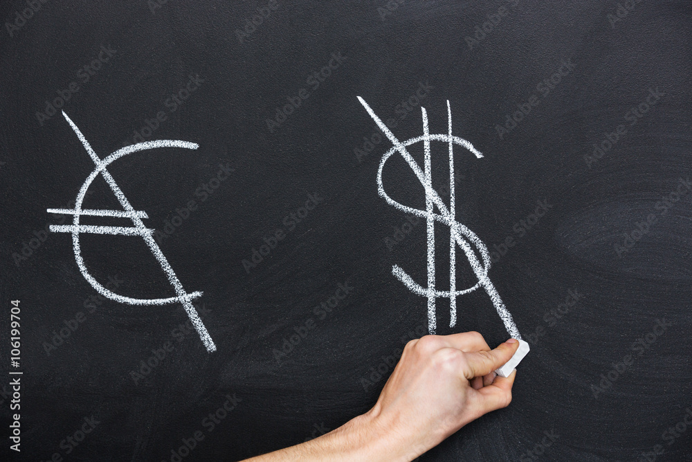 Signs of euro and dollar crossed on blackboard by hand