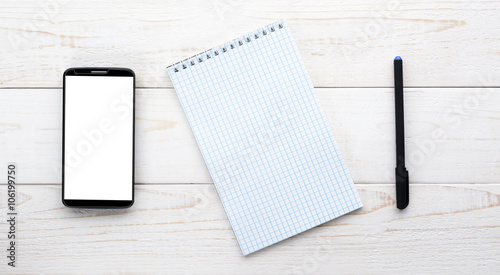 Smartphone, notebook with pen on a white table