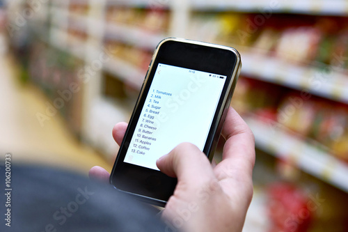 Shopping list on smartphone screen in hand of customers