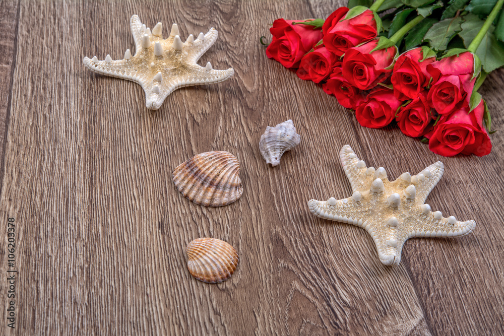 Starfishes, shells and red roses on a wooden background Starfishes, shells and red roses on a wooden background