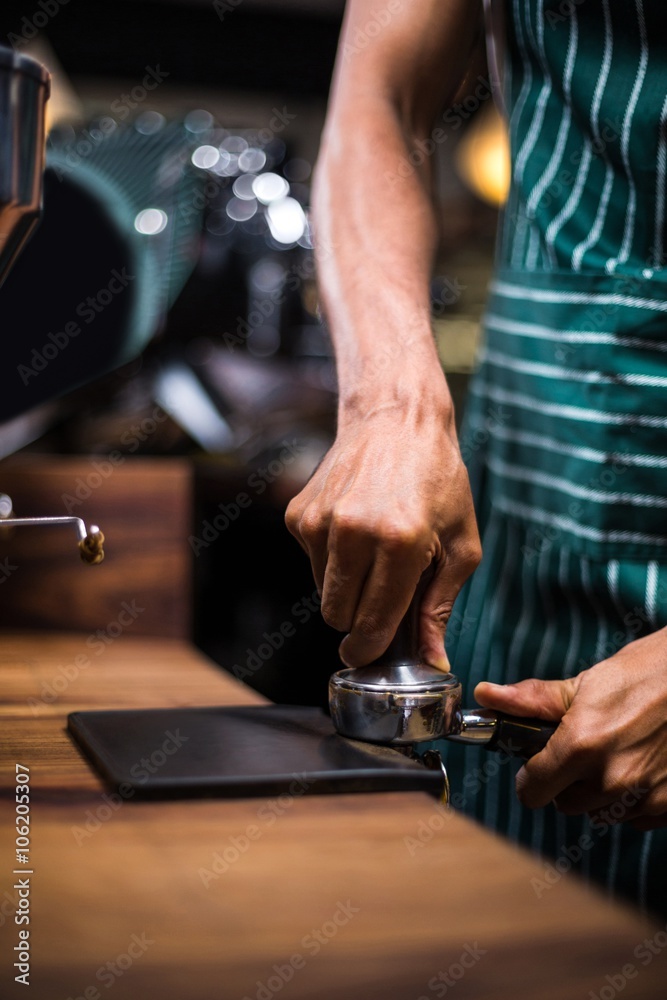 Waiter squeezing the coffee in the percolator