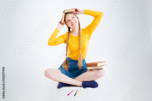 Happy female student sitting on the floor with book