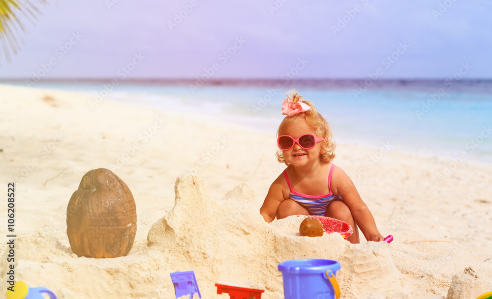 cute little girl playing with sand on beach - obrazy, fototapety, plakaty 