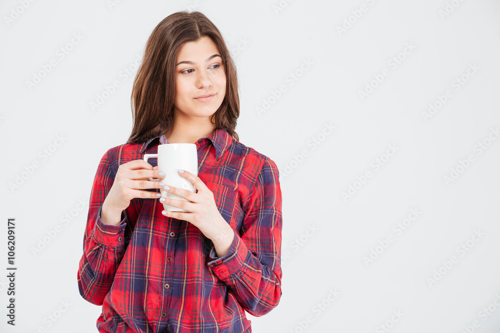 Thoughtful pretty young woman in plaid shirt holding white mug Thoughtful pretty young woman in plaid shirt holding white mug