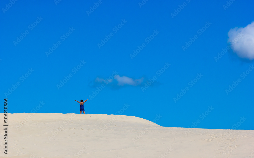 Mulher de braços abertos na dunas.