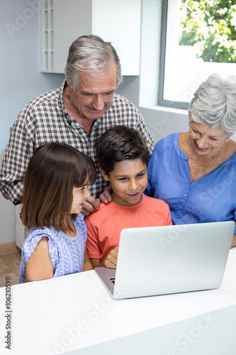 Grand parents and grandchildren interacting using laptop