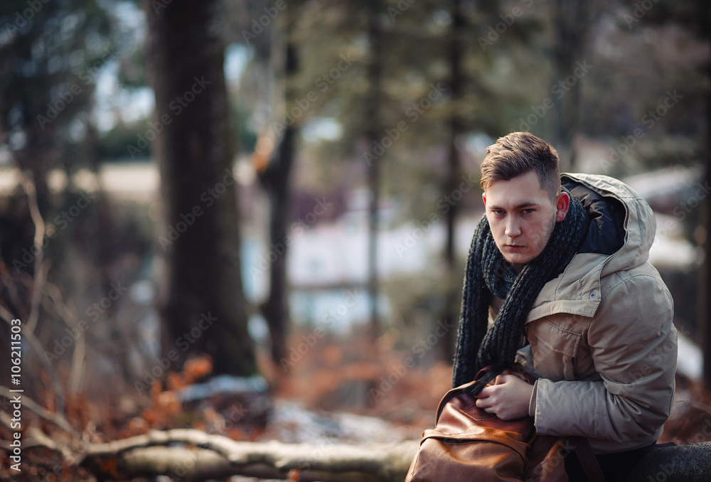 young guy in a warm cap and a jacket with a scarf on the neck, trousers and rubber boots walks alone in the Carpathian mountains with a camera, a tripod and a backpack on his shoulders young guy in a warm cap and a jacket with a scarf on the neck, trousers and rubber boots walks alone in the Carpathian mountains with a camera, a tripod and a backpack on his shoulders