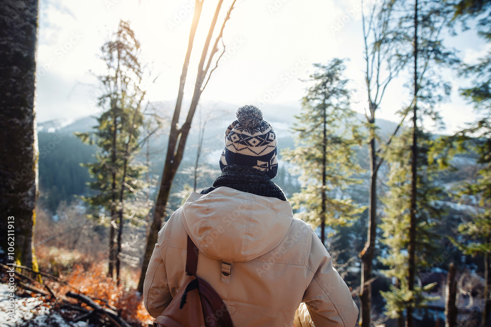 young guy in a warm cap and a jacket with a scarf on the neck, trousers and rubber boots walks alone in the Carpathian mountains with a camera, a tripod and a backpack on his shoulders young guy in a warm cap and a jacket with a scarf on the neck, trousers and rubber boots walks alone in the Carpathian mountains with a camera, a tripod and a backpack on his shoulders