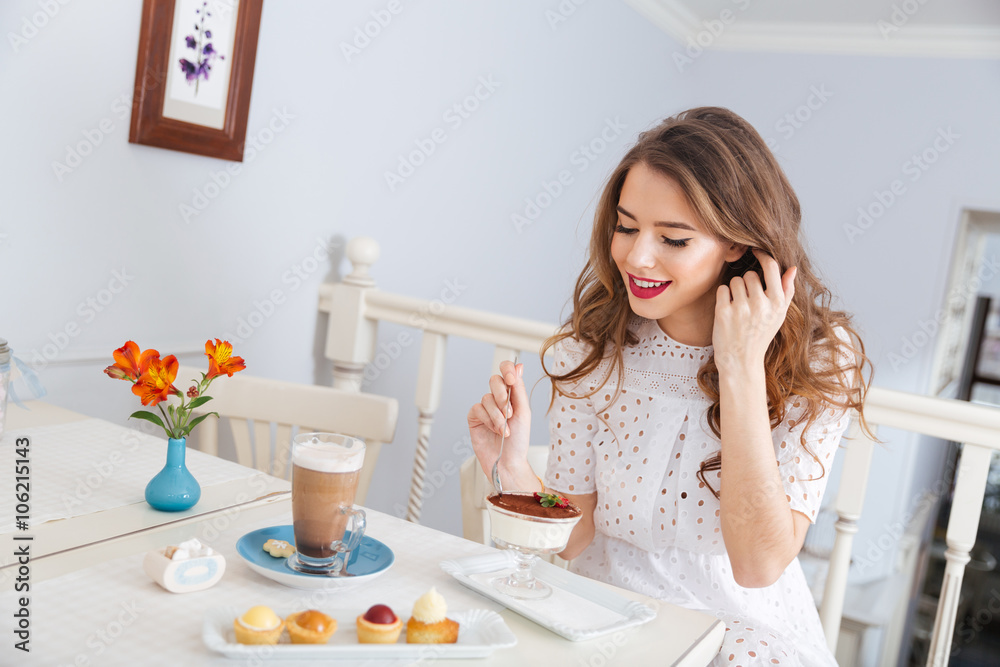 Smiling woman eating dessert and drinking latte in cafe Smiling woman eating dessert and drinking latte in cafe