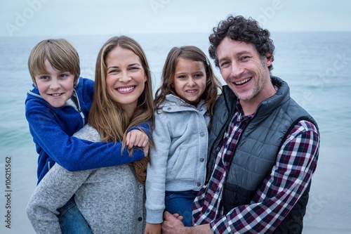 Parents smiling while carrying children at sea shore