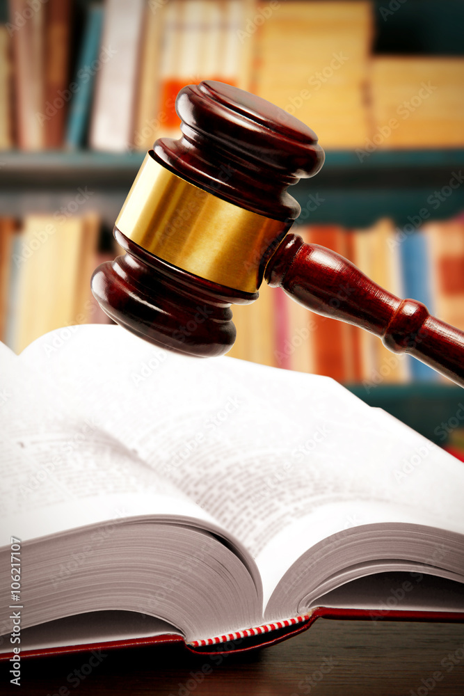 Judge gavel and book on table on book shelves background Judge gavel and book on table on book shelves background